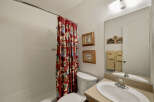 This charming bathroom features a cozy design with a red patterned shower curtain, adding a touch of personality to the space.