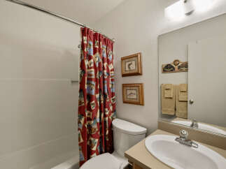 This charming bathroom features a cozy design with a red patterned shower curtain, adding a touch of personality to the space.