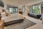 Experience luxury in this stunning bedroom featuring a plush bed, a stylish black leather sofa, and expansive windows that frame breathtaking views of the surrounding nature.