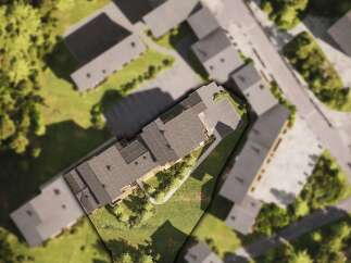 This aerial view showcases a modern apartment complex nestled in a serene, green environment.