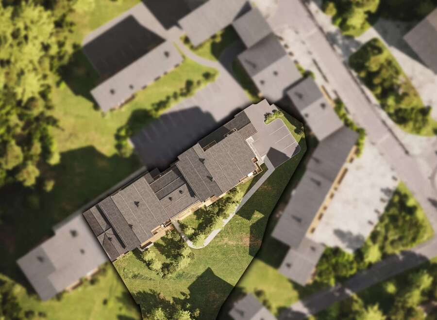 This aerial view showcases a modern apartment complex nestled in a serene, green environment.