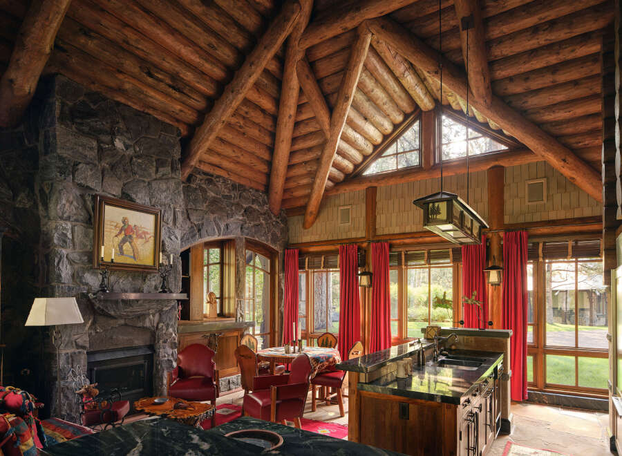 Step into rustic elegance with this stunning property, showcasing a grand stone fireplace and a soaring, exposed-beam ceiling.