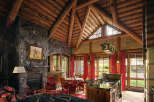 Step into rustic elegance with this stunning property, showcasing a grand stone fireplace and a soaring, exposed-beam ceiling.