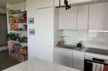 This modern kitchen boasts sleek, white cabinetry and a minimalist design, perfect for contemporary living.