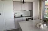 This modern kitchen boasts sleek, white cabinetry and a stunning quartz countertop, perfect for culinary enthusiasts.