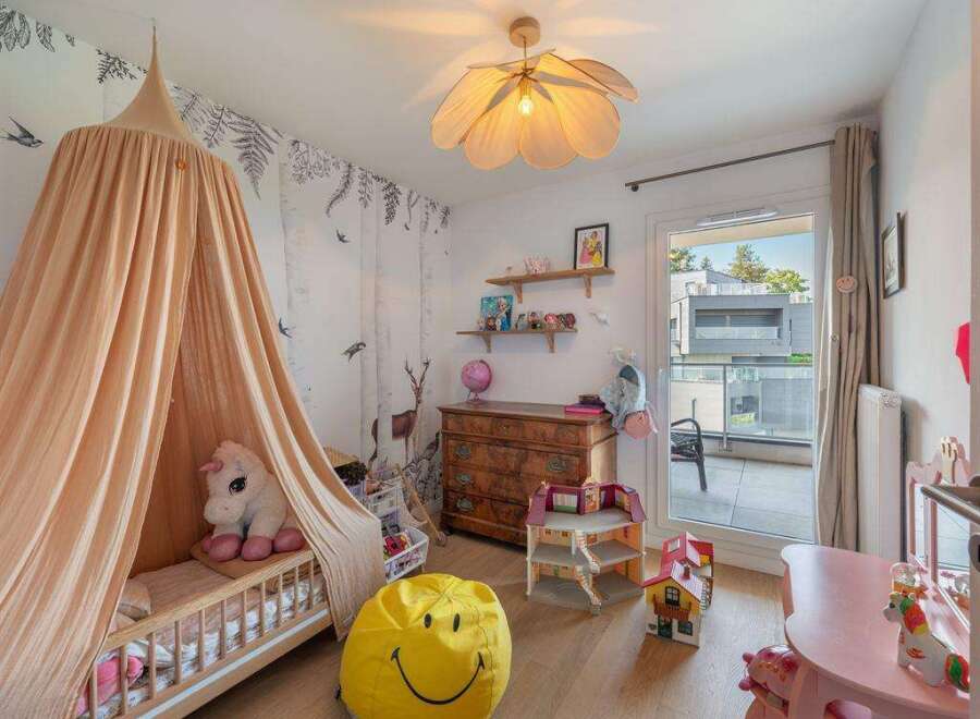This charming children's bedroom features a whimsical design with a canopy bed, a smiley face beanbag, and a dollhouse.
