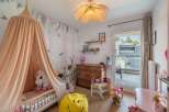 This charming children's bedroom features a whimsical design with a canopy bed, a smiley face beanbag, and a dollhouse.