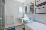 This modern bathroom features a sleek design with a double sink vanity and a washing machine.