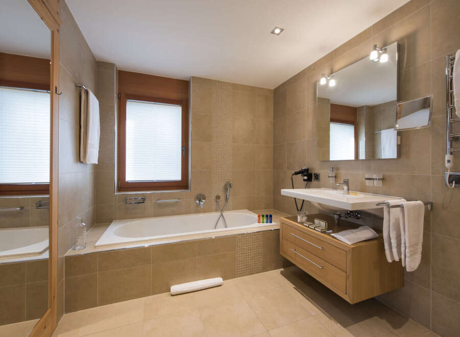 This luxurious bathroom features a modern design with a sleek bathtub, a stylish vanity, and a large mirror.
