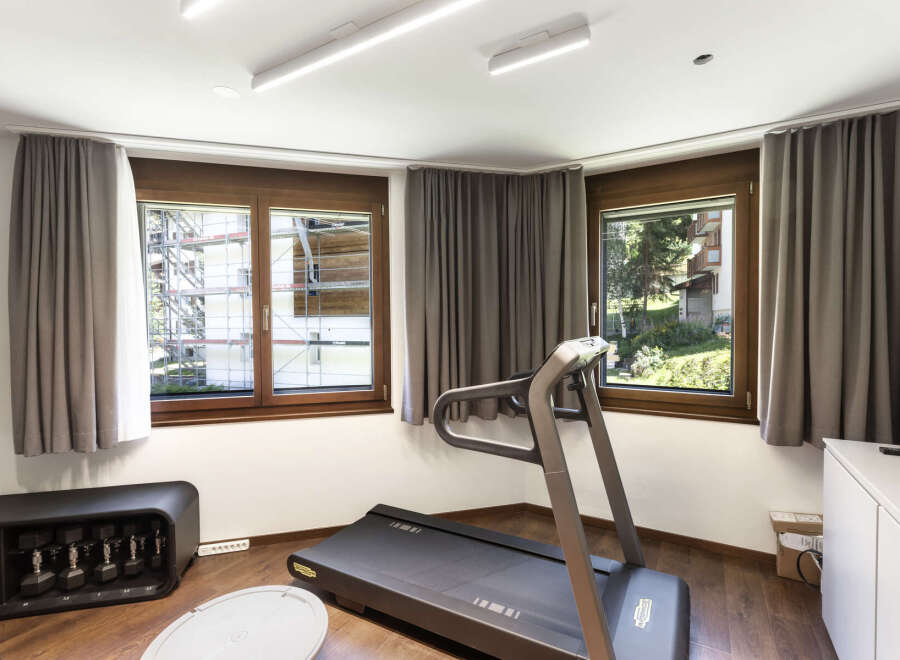 This home gym offers a bright and airy space for workouts, featuring a modern treadmill and ample natural light.