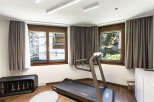 This home gym offers a bright and airy space for workouts, featuring a modern treadmill and ample natural light.