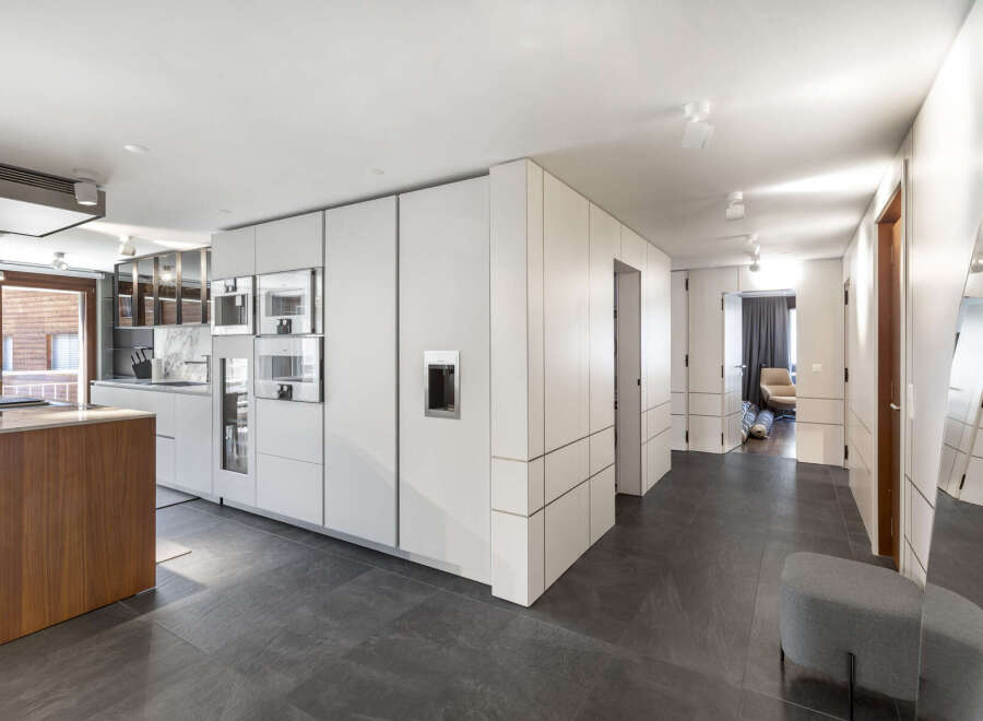 This modern kitchen boasts sleek, white cabinetry and integrated appliances, creating a seamless and stylish design.