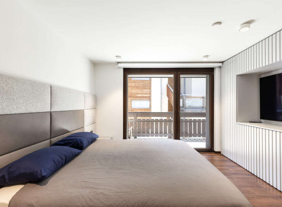 This modern bedroom features a stylish design with a comfortable bed and a sleek built-in TV.