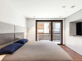 This modern bedroom features a stylish design with a comfortable bed and a sleek built-in TV.