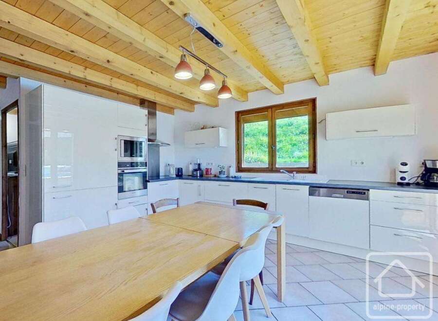 This stunning kitchen boasts a modern design with sleek white cabinetry and a warm wooden ceiling.