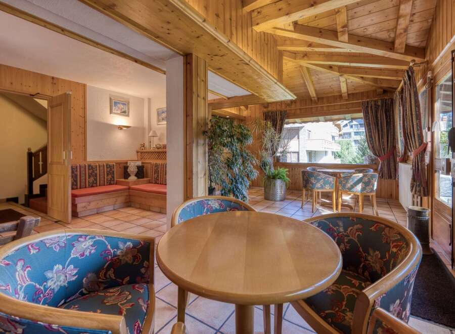 This cozy interior features a charming seating area with round wooden tables and patterned chairs, perfect for intimate gatherings.