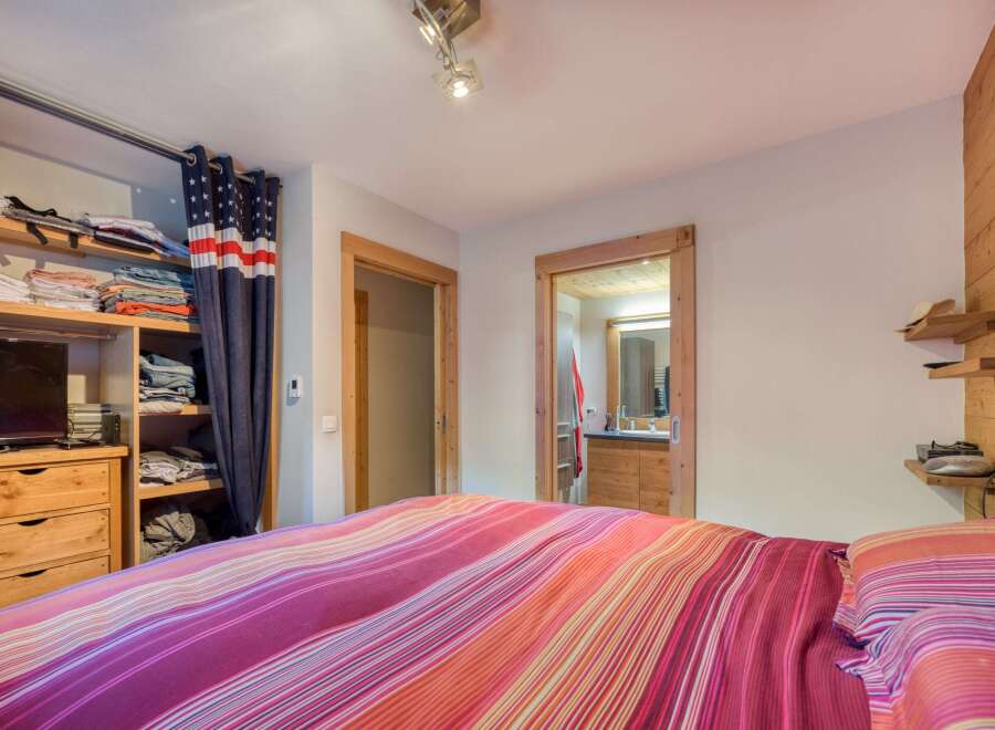 This cozy bedroom features a unique American flag-themed curtain and a vibrant, striped bedspread, creating a warm and inviting atmosphere.