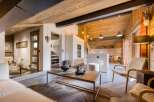 Experience the warmth of this stunning chalet, featuring a cozy living area with a rustic wooden ceiling and a modern kitchen.