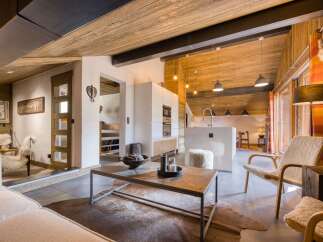 Experience the warmth of this stunning chalet, featuring a cozy living area with a rustic wooden ceiling and a modern kitchen.