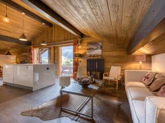 This stunning property boasts a cozy living space with a rustic wooden ceiling and walls, creating a warm and inviting atmosphere.