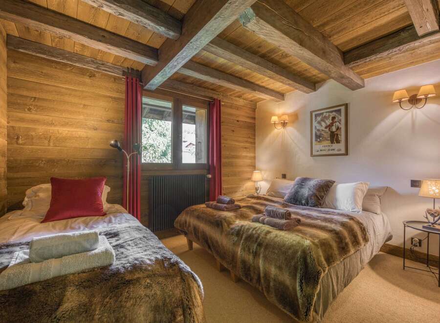 This cozy bedroom features rustic wooden walls and ceiling beams, creating a warm and inviting atmosphere.