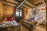 This cozy bedroom features rustic wooden walls and ceiling beams, creating a warm and inviting atmosphere.