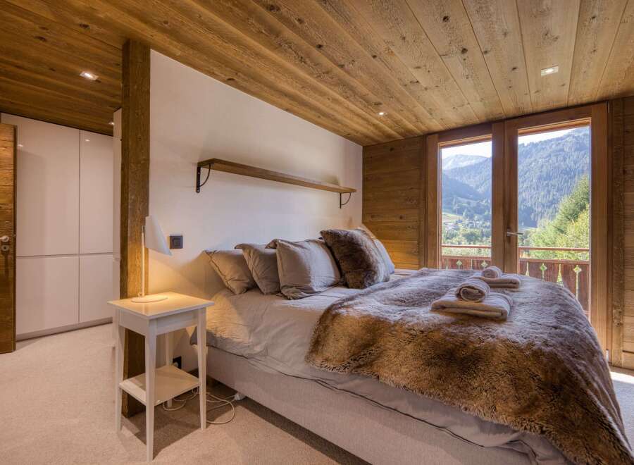 This cozy bedroom features a stunning wooden ceiling and walls, creating a warm and inviting atmosphere.
