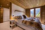 This cozy bedroom features a stunning wooden ceiling and walls, creating a warm and inviting atmosphere.