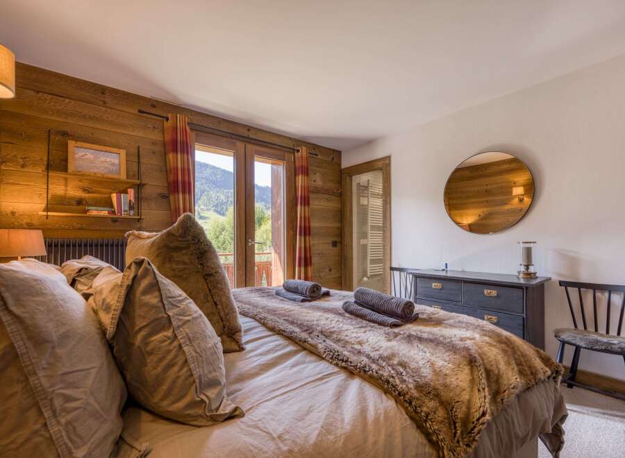 This cozy bedroom features rustic wood paneling and a luxurious faux fur throw, creating a warm and inviting atmosphere.