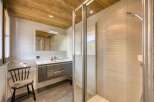 This modern bathroom features a sleek, gray vanity with ample storage and a stylish black chair with a fur seat.