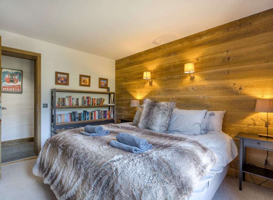 This cozy bedroom features a rustic wooden accent wall and a plush, inviting bed.