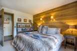 This cozy bedroom features a rustic wooden accent wall and a plush, inviting bed.