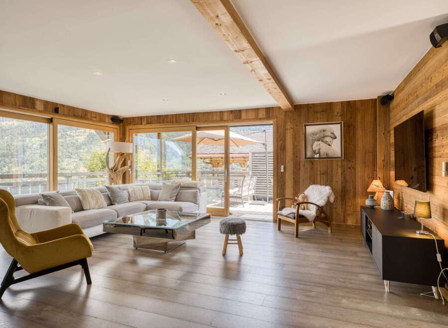 This stunning living room boasts a warm and inviting atmosphere with its wooden paneling and large windows offering breathtaking views.