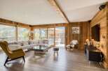 This stunning living room boasts a warm and inviting atmosphere with its wooden paneling and large windows offering breathtaking views.