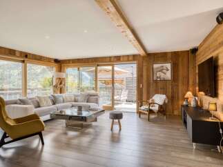 This stunning living room boasts a warm and inviting atmosphere with its wooden paneling and large windows offering breathtaking views.