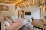 This cozy bedroom features a wooden ceiling and a comfortable bed with soft pink bedding.