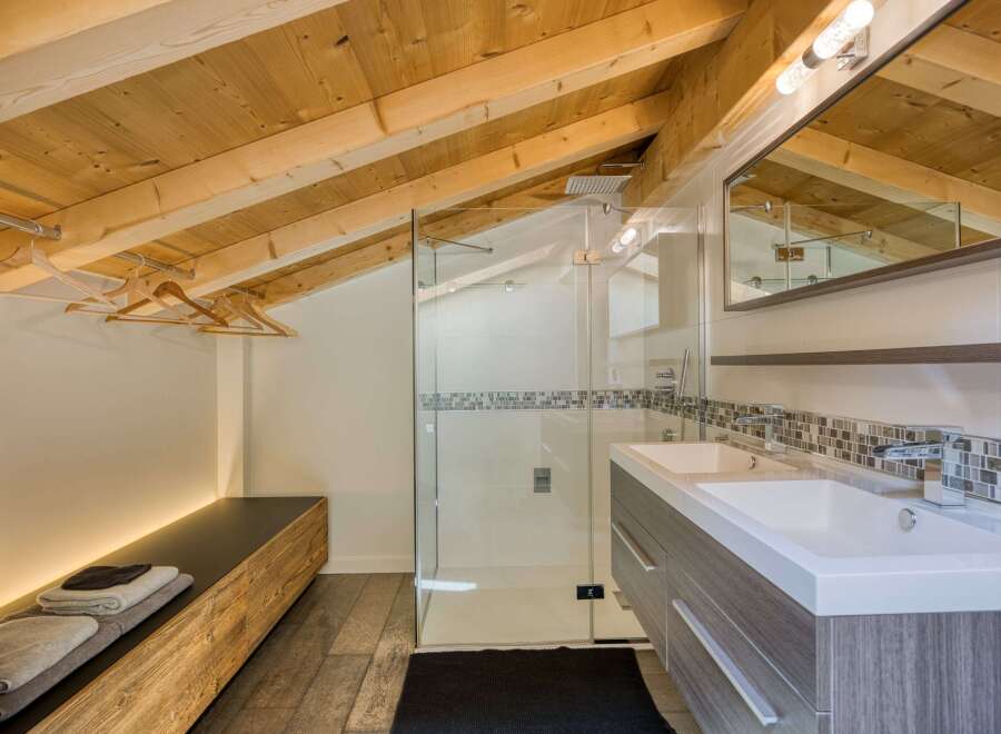 This stunning bathroom features a unique design with a wooden sloped ceiling, creating a warm and inviting atmosphere.