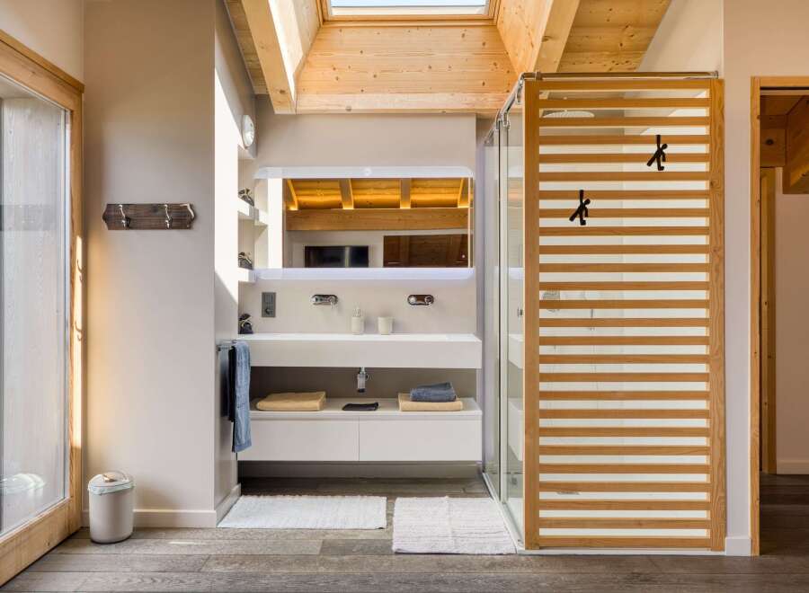 This modern bathroom features a sleek design with a wooden slatted shower door and a skylight that floods the space with natural light.