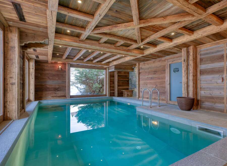 This luxurious indoor pool area showcases rustic elegance with its wooden beams and paneling.