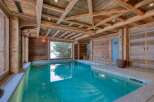 This luxurious indoor pool area showcases rustic elegance with its wooden beams and paneling.