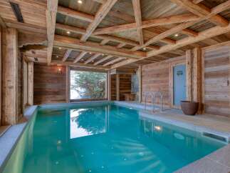 This luxurious indoor pool area showcases rustic elegance with its wooden beams and paneling.