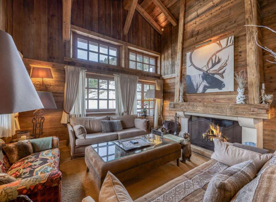 Experience the warmth of this stunning chalet-style living room, featuring rustic wooden walls and a cozy fireplace.