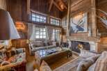 Experience the warmth of this stunning chalet-style living room, featuring rustic wooden walls and a cozy fireplace.