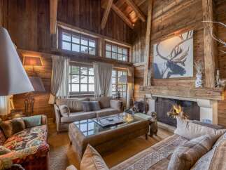 Experience the warmth of this stunning chalet-style living room, featuring rustic wooden walls and a cozy fireplace.