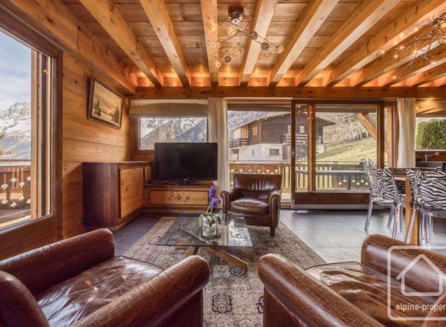 Experience the charm of this stunning property, featuring a cozy living room with exposed wooden beams and a breathtaking mountain view.