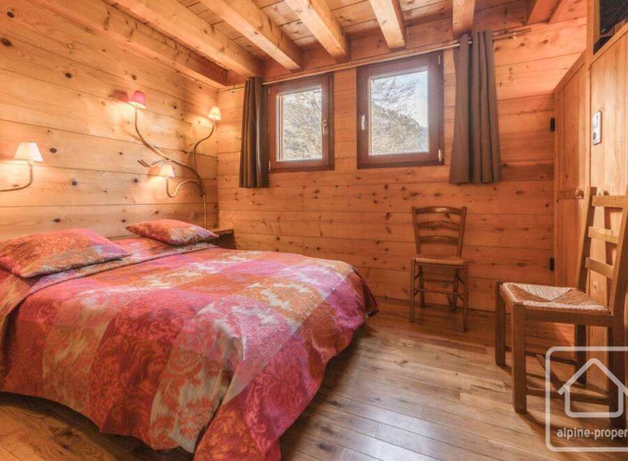 Experience the warmth of this charming bedroom, featuring rustic wooden walls and a cozy ambiance.