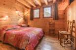 Experience the warmth of this charming bedroom, featuring rustic wooden walls and a cozy ambiance.