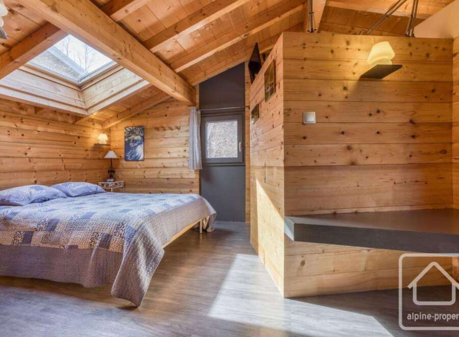 Discover the charm of this cozy bedroom, featuring stunning wooden paneling and a unique skylight that floods the space with natural light.