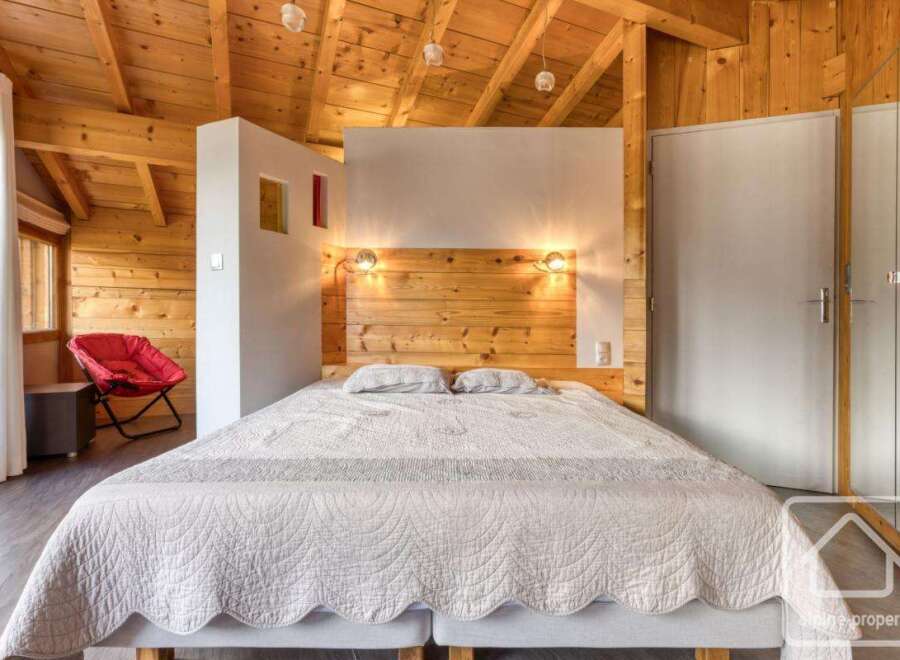 This cozy bedroom features a wooden ceiling and walls, creating a warm and inviting atmosphere.