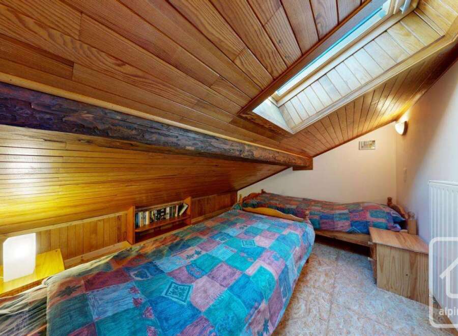 Discover the charm of this cozy bedroom, featuring a unique wooden ceiling and a skylight that fills the space with natural light.
